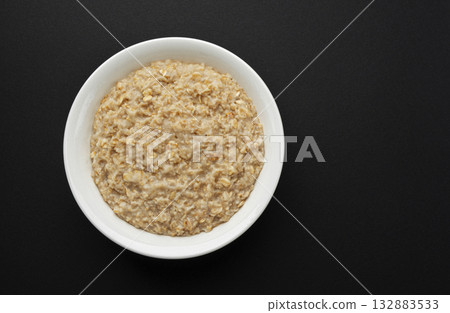 Bowl of oatmeal on black background, oat porridge breakfast, top view Bowl of oatmeal on black background, oat porridge breakfast, top view 132883533