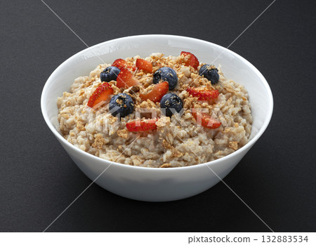 Bowl of oatmeal with berries on black background, oat porridge breakfast 132883534