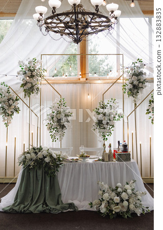 Elegant wedding banquet hall with floral decor and white drapery under wooden ceiling 132883835