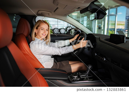 Happy woman sitting in new car at dealership 132883861