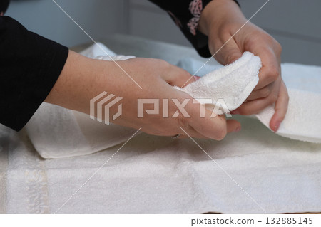 A woman is unboxing and reviewing a gift set of two towels. She is demonstrating the quality of the product. 132885145