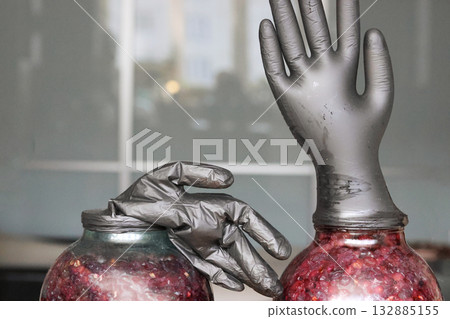 Two glass jars with fermenting grapes. Black rubber gloves are put on the jars. One glove is inflated by fermentation gases. Making homemade grape wine. Close-up.. Two glass jars with fermenting grapes. Black rubber gloves are put on the jars. One glove is inflated by fermentation gases. Making homemade grape wine. Close-up.. 132885155