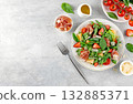 Green salad with prosciutto, arugula, strawberries, melon, tomatoes, parmesan on gray background. Top view. Copy space. 132885371