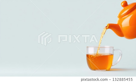 Orange Teapot Pouring Tea into Glass Cup 132885455