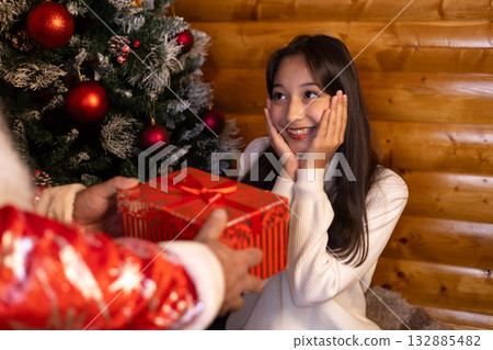A woman joyfully receives a Christmas present A woman joyfully receives a Christmas present 132885482