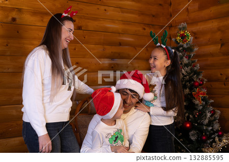 The family is joyfully posing for a Christmas photo in front of a decorated tree 132885595