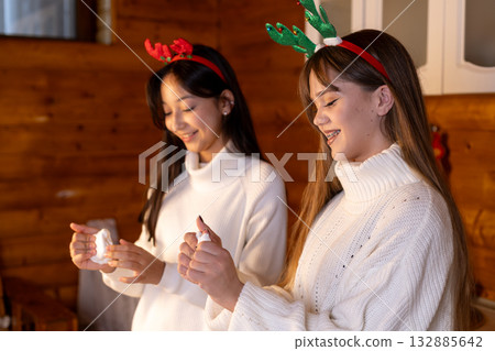 Two friends are smiling while celebrating Christmas together Two friends are smiling while celebrating Christmas together 132885642