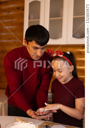 A father and daughter are decorating Christmas cookies together in the kitchen A father and daughter are decorating Christmas cookies together in the kitchen 132885673
