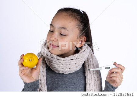 The girl is smiling while holding a lemon and a thermometer The girl is smiling while holding a lemon and a thermometer 132885681
