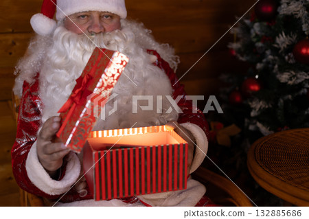 Santa Claus holds a gift box with a lit candle Santa Claus holds a gift box with a lit candle 132885686