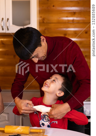 A father and his child are joyfully baking Christmas cookies together A father and his child are joyfully baking Christmas cookies together 132885689