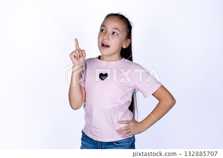 The girl is pointing her finger up and looking to the side with a surprised The girl is pointing her finger up and looking to the side with a surprised 132885707