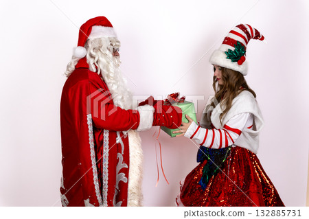 Santa Claus and his elf are exchanging a gift during the Christmas season 132885731