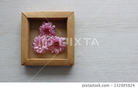 Textured white oak plank and craft cardboard case with soft flowering flowers copy space stock photo Textured white oak plank and craft cardboard case with soft flowering flowers copy space stock photo 132885824