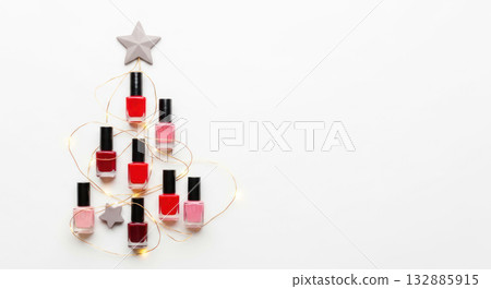 Creative arrangement of nail polish bottles shaped like a Christmas tree with decorative star and fairy lights, perfect for festive beauty themes 132885915
