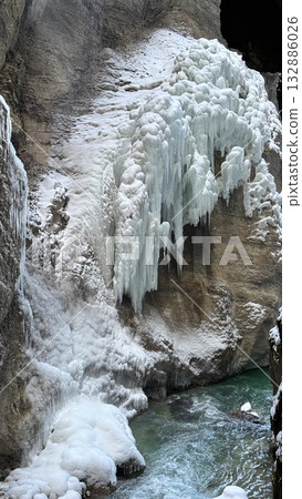 Frozen waterfall in Partnachklamm, Garmisch-Partenkirchen cascading down rocky cliff in winter Frozen waterfall in Partnachklamm, Garmisch-Partenkirchen cascading down rocky cliff in winter 132886026