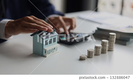 Investing in Real Estate, Real estate agent or investor calculating, planning, analyzing financial data for property investment. Themes of saving, investing, financial aspects of purchasing a home. 132886047