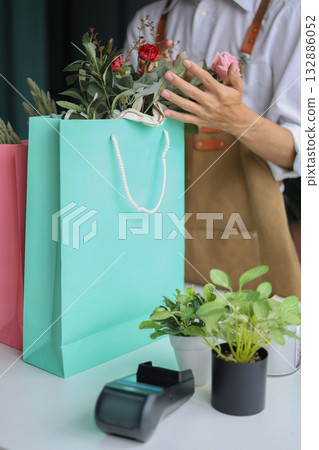 A florist working in retail shop preparing order put in shopping bags for customer. 132886052