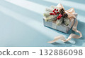 Christmas gift box with snowy fir branches, pine cones, and red berries on blue background. 132886098
