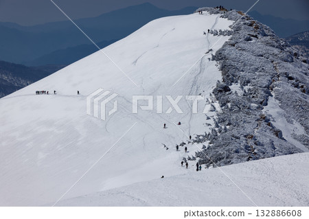 Mount Koshibutsu and climbers seen from the top of Mount Shibutsu during the snowy season 132886608