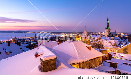 黃昏時分,白雪覆蓋的屋頂和靜謐冬日小鎮的燈光交相輝映。 黃昏時分,白雪覆蓋的屋頂和靜謐冬日小鎮的燈光交相輝映。 132886766