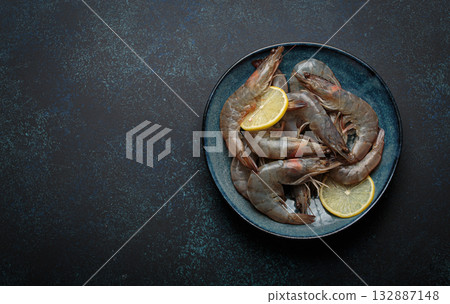 Fresh raw shrimps prawns lemon slices plate dark background seafood uncooked healthy 132887148