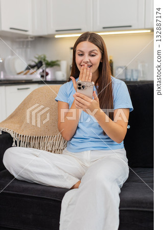Young woman gets offer message on smartphone covers mouth joy signs contract and sends agree reply Young woman gets offer message on smartphone covers mouth joy signs contract and sends agree reply 132887174