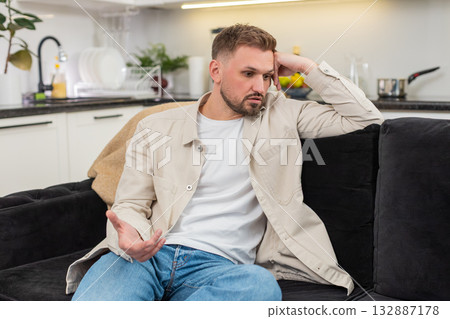 Young man with exhausted mood after rough day sits quiet and reflects on stress low energy and calm Young man with exhausted mood after rough day sits quiet and reflects on stress low energy and calm 132887178