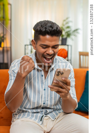 Indian man celebrates online game win after smartphone alert shows prize news joyful happy reaction 132887188