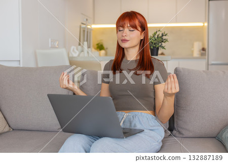 Young woman takes break from laptop work does meditation deep breathing and tries to calm down focus Young woman takes break from laptop work does meditation deep breathing and tries to calm down focus 132887189