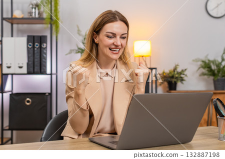 Businesswoman gets project approval message on laptop good news celebrates success victory gesture Businesswoman gets project approval message on laptop good news celebrates success victory gesture 132887198