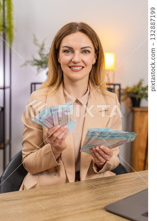Rich businesswoman counts money hryvnia cash amazed by high salary income bonus rise profit stack Rich businesswoman counts money hryvnia cash amazed by high salary income bonus rise profit stack 132887199