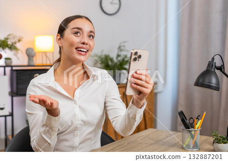 Young businesswoman starts selfie stream on smartphone waves hand says hi and chats with followers Young businesswoman starts selfie stream on smartphone waves hand says hi and chats with followers 132887201