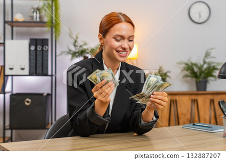 Young businesswoman happily counts dollar income proud of salary bonus and bright financial success Young businesswoman happily counts dollar income proud of salary bonus and bright financial success 132887207