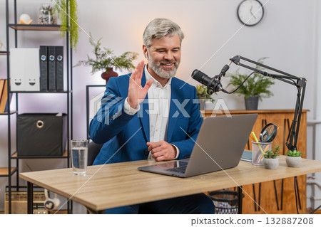 Middle-aged businessman records podcast on studio microphone gesturing actively sharing live ideas 132887208