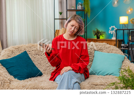 Young woman receiving bad news on smartphone screen, looking upset, disappointed shaking head sadly 132887225
