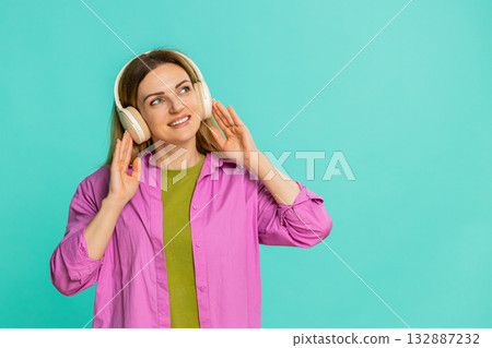 Woman putting on wireless headphones starts moving to rhythm enjoying music and feeling the beat Woman putting on wireless headphones starts moving to rhythm enjoying music and feeling the beat 132887232