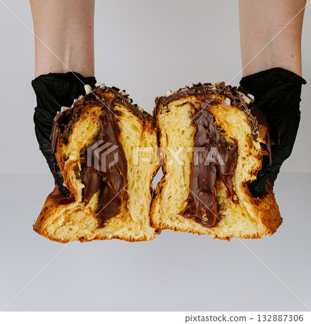 Hands in gloves holding sliced chocolate filled Christmas panettone, bakery hygiene concept Hands in gloves holding sliced chocolate filled Christmas panettone, bakery hygiene concept 132887306