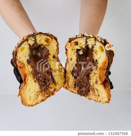 Hands in gloves holding sliced chocolate filled Christmas panettone, bakery hygiene concept 132887308