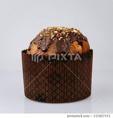 Christmas panettone with chocolate glaze and nuts on white background, festive dessert Christmas panettone with chocolate glaze and nuts on white background, festive dessert 132887331