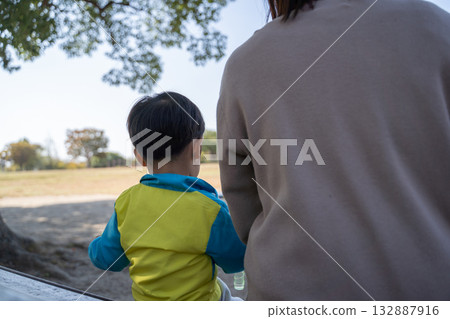 父母和孩子在公園長椅上休息。 父母和孩子在公園長椅上休息。 132887916