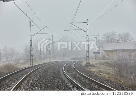 Double track railway main line rails in winter frost snow and fog 132888589