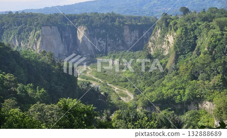 A stunning viewpoint at Panorama Ngarai Sianok showcases lush greenery, towering trees, and a majestic mountain under the clear blue sky A stunning viewpoint at Panorama Ngarai Sianok showcases lush greenery, towering trees, and a majestic mountain under the clear blue sky 132888689