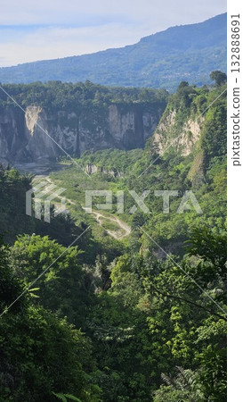A stunning viewpoint at Panorama Ngarai Sianok showcases lush greenery, towering trees, and a majestic mountain under the clear blue sky A stunning viewpoint at Panorama Ngarai Sianok showcases lush greenery, towering trees, and a majestic mountain under the clear blue sky 132888691