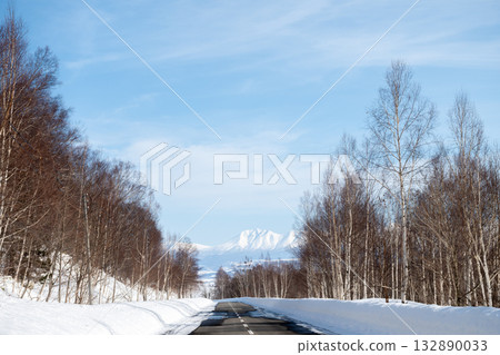 Snow starting to melt on the road and snow-capped mountains of the Tokachi mountain range Snow starting to melt on the road and snow-capped mountains of the Tokachi mountain range 132890033