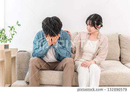 Woman comforting a depressed man on the sofa, couple Woman comforting a depressed man on the sofa, couple 132890579