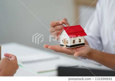 Real Estate Consultation. Agent presenting a miniature house model to a client. 132890692