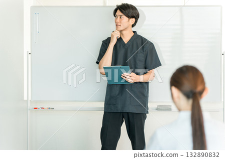 Male staff including doctors, nurses, and pharmacists explaining in front of a whiteboard at a medical conference 132890832