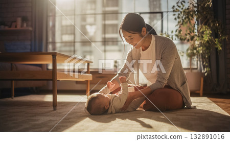 Portrait of a smiling mother and baby in a bright living room 132891016