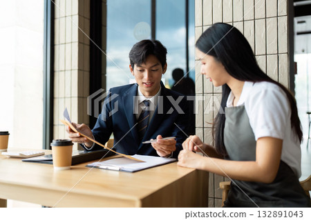 Business Meeting and Collaboration. Professional man and woman discussing project details at a modern workspace. 132891043